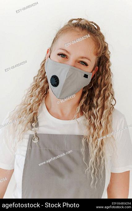 Close up portrait of Caucasian middle-aged woman in working uniform mask and apron looking at camera. White background