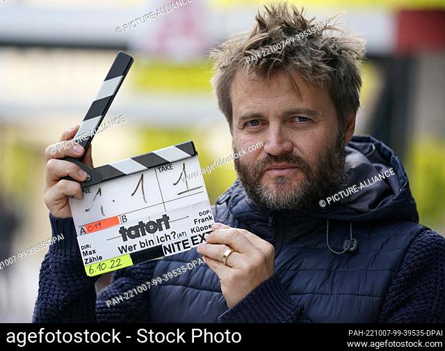 06 October 2022, Hamburg: Director Max Zähle holds up a film flap with the words ""Tatort"" in front of the Mehndi Restaurant Bar in City Nord on the sidelines...