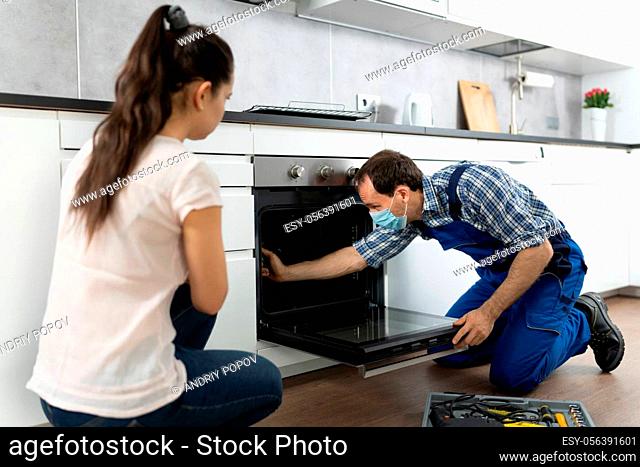 Kitchen Appliance Oven Repair By Handyman Technician In Face Mask