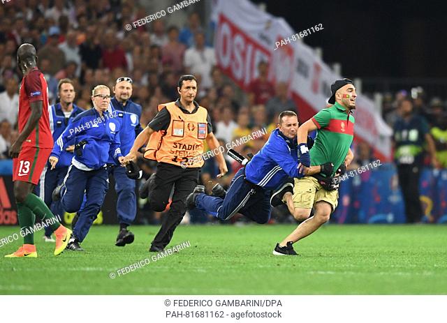 A steward and policemen try to catch a pitch invader during the UEFA EURO 2016 quarter final soccer match between Poland and Portugal at the Stade Velodrome in...