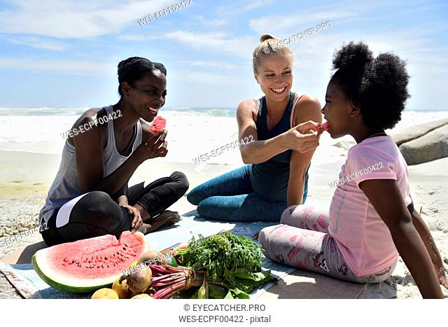 Mother with daughter and friend having a picnic on the beach