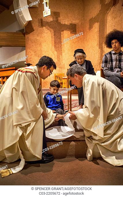 The robed pastor of St. Timothy's Catholic Church, Laguna Niguel, CA, washes the feet of a young parishioner on Holy Thursday mass in memory of Christ washing...