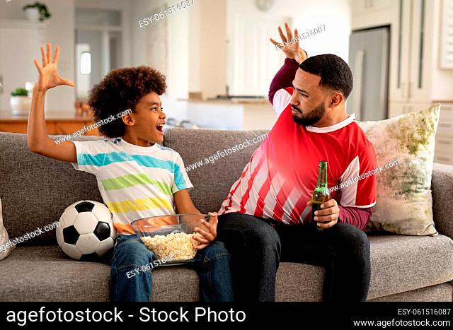 Man and son high fiving each other while watching sports on TV at home