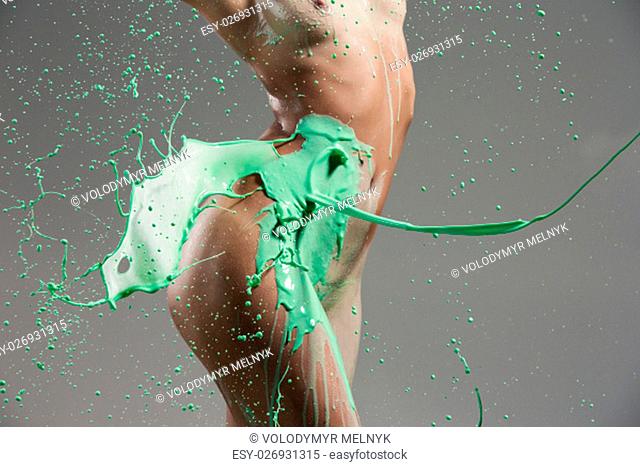 The beautiful woman with green liquid paint over her body on gray