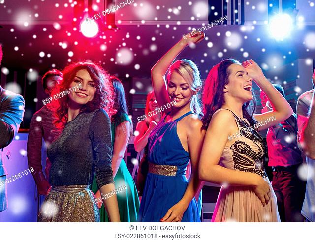 new year party, holidays, celebration, nightlife and people concept - smiling friends dancing in club and snow effect
