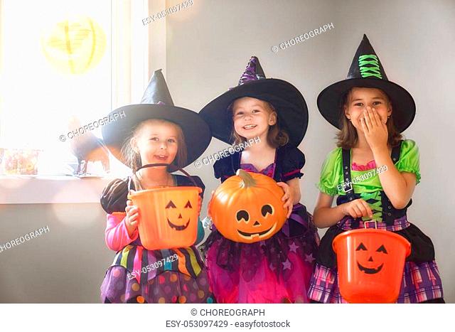 Happy Halloween! Three cute little laughing girls in witches costumes