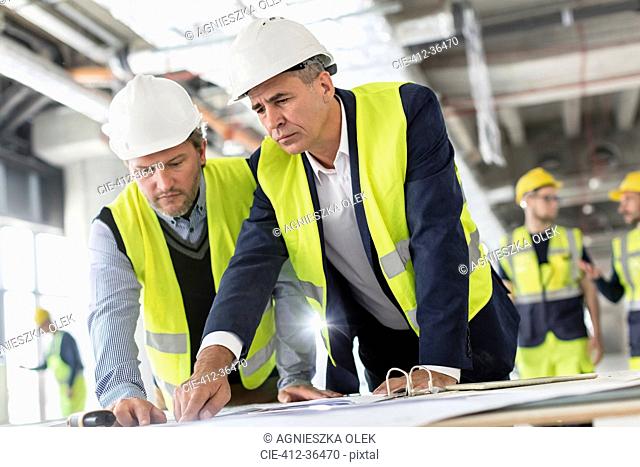 Male engineers viewing blueprints at construction site