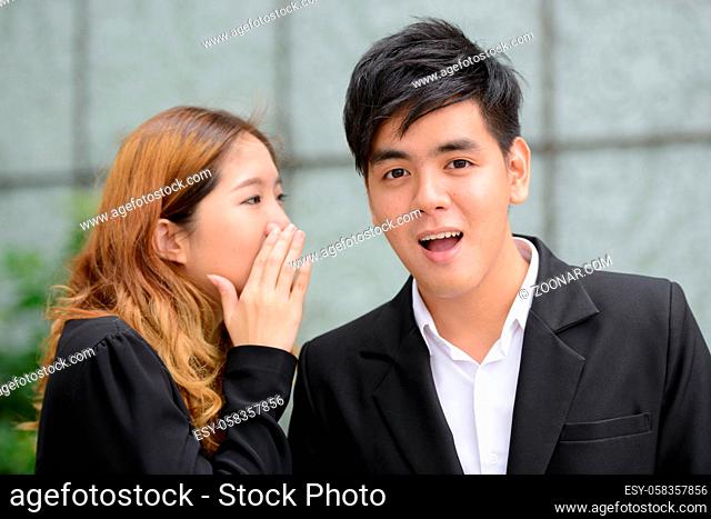 Portrait of young Asian businessman and young Asian businesswoman together in the city outdoors