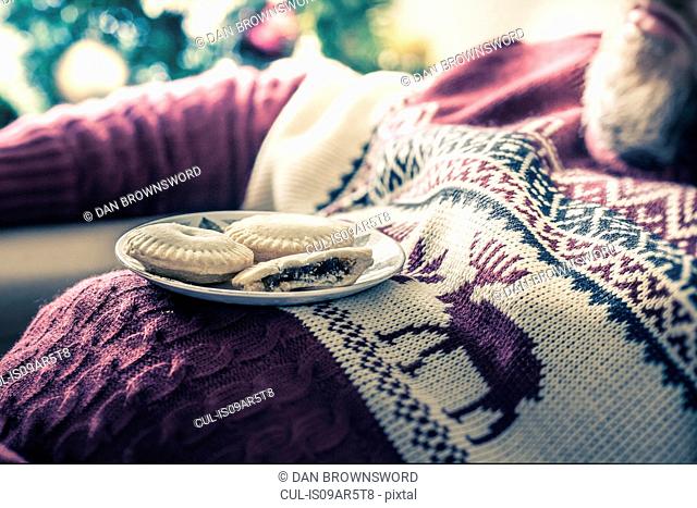 Man wearing sweater asleep with mince pies on chest