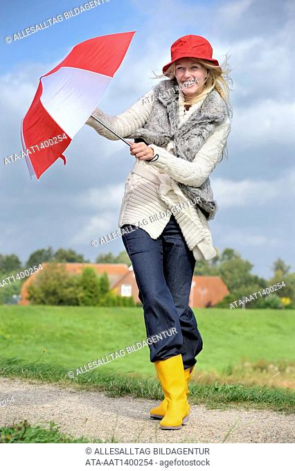 Woman walking with an umbrella against strong wind