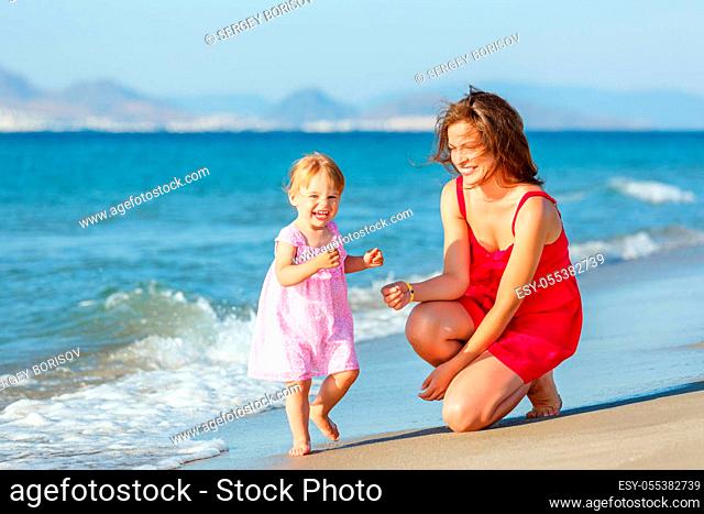 Mother with little daughter playing on the beach