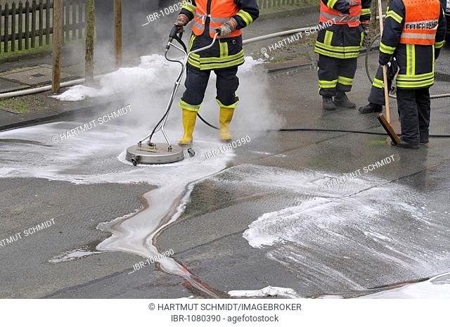 Fire brigade in action, firemen neutralising leaked brake fluid from a street