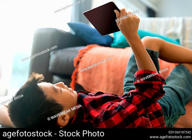Asian boy using tablet with blank screen lying on floor at home
