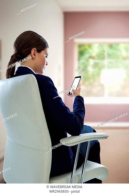 Businesswoman Back Sitting in Chair with mobile phone near window