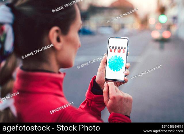 Woman wearing mask using her phone to read news about the Coronavirus situation