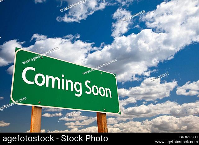 Coming soon green road sign with copy room over the dramatic clouds and sky