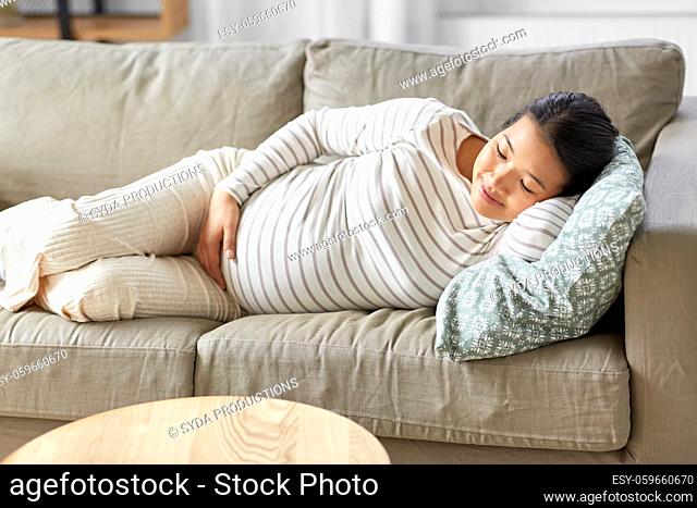 pregnant asian woman sleeping on sofa at home