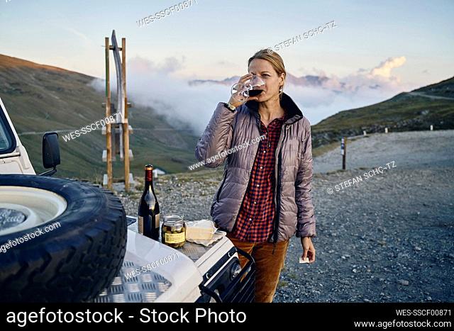 Tourist drinking red wine on road trip, Colle dell'Assietta, Turin, Italy