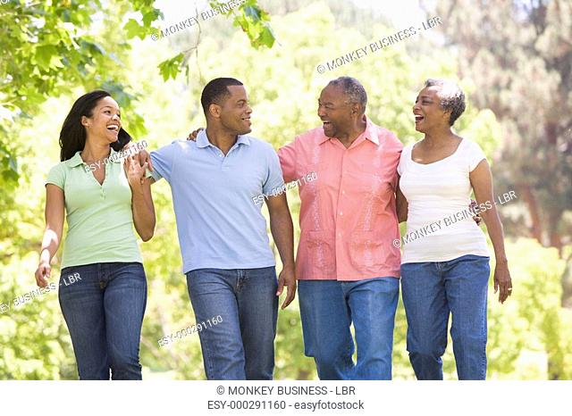 Two couples walking outdoors arm in arm smiling