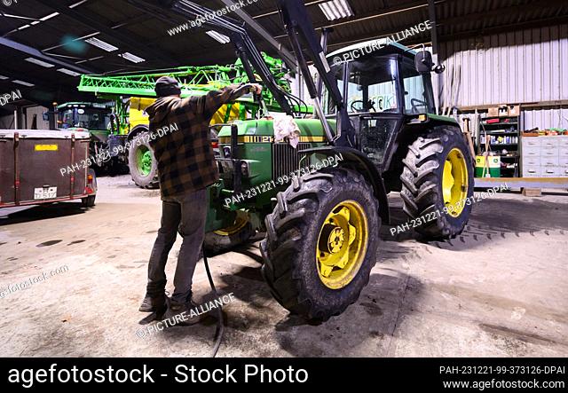 21 December 2023, Lower Saxony, Hanover: A farmer in the Hanover region fills up a wheel loader with diesel in his vehicle shed