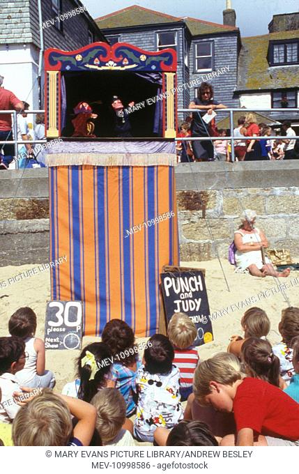 Children watching a Punch and Judy show on the beach, Cornwall