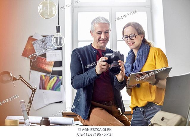 Photographers using digital tablet and digital camera in office