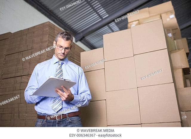 Manager with clipboard in warehouse