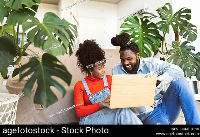 Smiling couple with laptop talking in living room