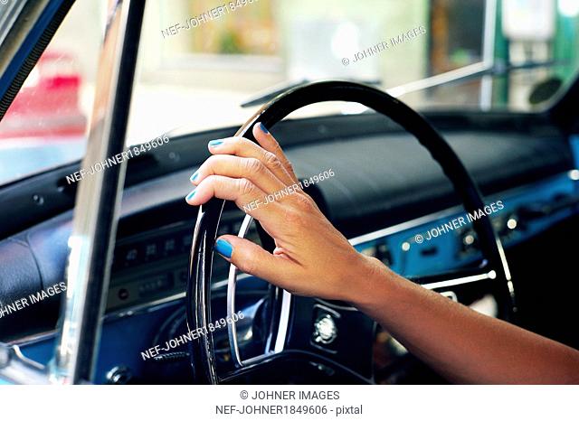 Womans hand on steering wheel, close-up