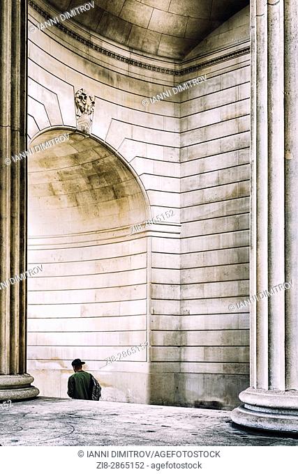 Person walks under the arch of The Bank Of England , City of London, England