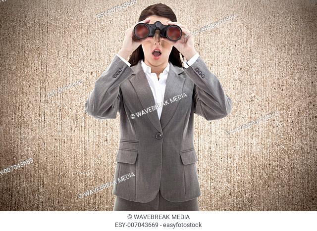 Composite image of surprised businesswoman looking through binoculars