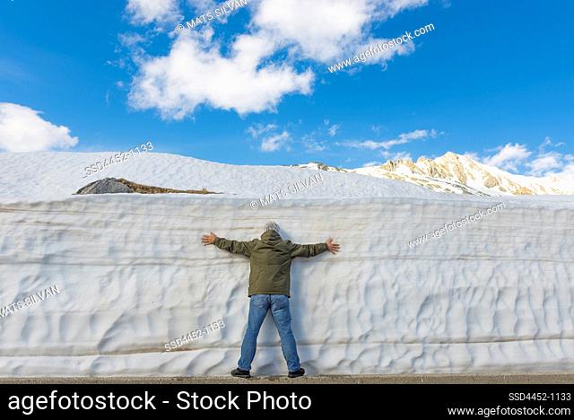 Man Leaning on a Snow Wall with Arms Outstretched in Uri, Switzerland