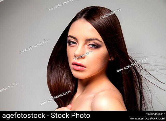 Young pretty brunette woman looking at camera. Horizontal studio shot