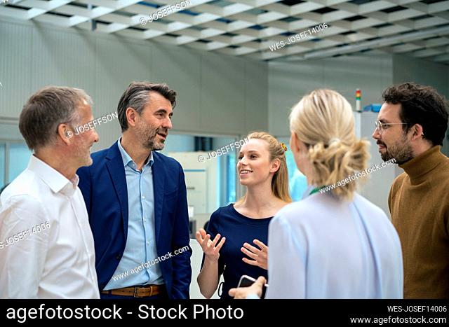 Young businesswoman gesturing and talking with colleagues at industry