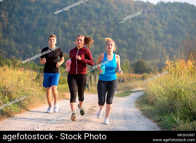 group of young people jogging on country road runners running on open road on a summer day