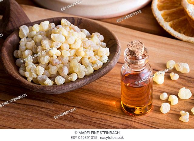 A bottle of frankincense essential oil with frankincense resin in the background