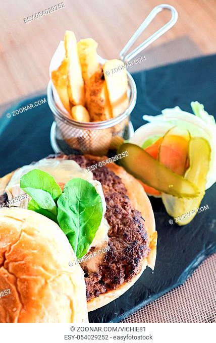 Homemade overload beef hamburger with fresh vegetables and cheese with fries