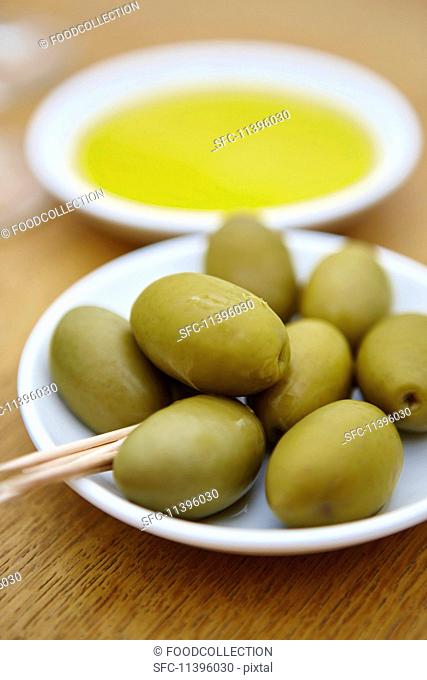 Green olives with wooden sticks on a plate