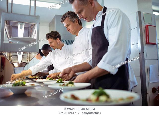 Team of chefs garnishing meal on counter