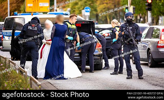 01 October 2023, Lower Saxony, Hanover: Police officers check participants of a wedding procession and their vehicles. Passers-by reported hearing shots coming...