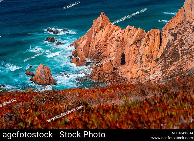 Praia do Ursa beach with beautiful orange colored cliffs on Atlantic ocean coast near popular touristic Cabo da Roca lighthouse, Portugal