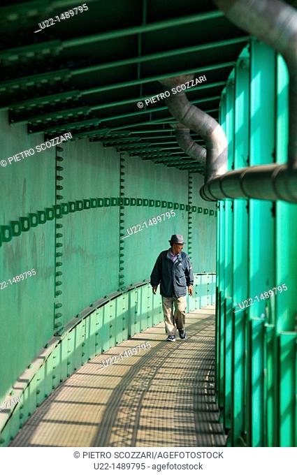 Busan (South Korea): a man crossing the trains tracks along a footbridge in Nam-gu neighborhood
