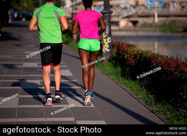 healthy young multiethnic couple jogging in the city on a sunny summer day