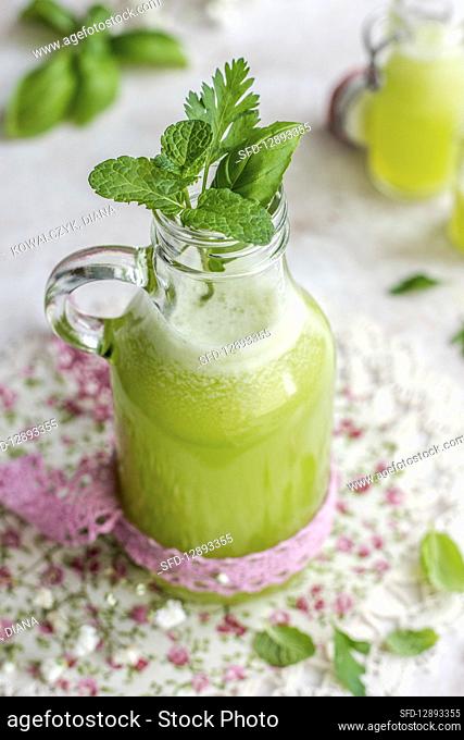 Green juice with basil and mint in a bottle with a pink ribbon
