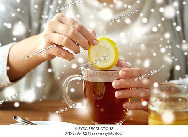 close up of woman adding lemon to tea with honey