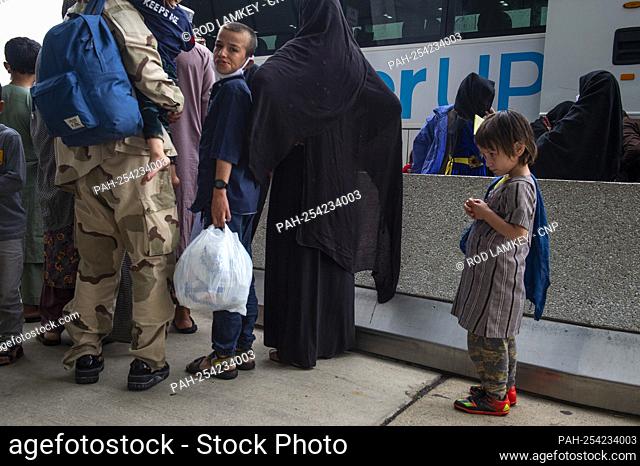 Refugees evacuated from Afghanistan arrive at Washington Dulles International Airport and make their way to a waiting bus in Chantilly, Virginia, Wednesday