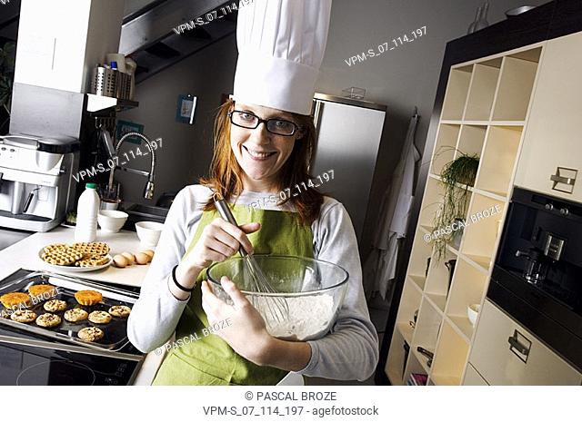 Portrait of a young woman holding a mixing bowl and smiling