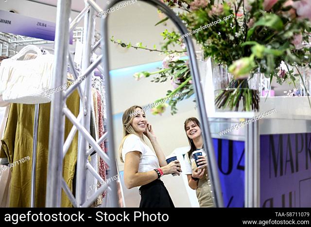 RUSSIA, MOSCOW - APRIL 28, 2023: Women are reflected in a mirror during the Moscow Fashion Week at the Oceania Shopping Centre
