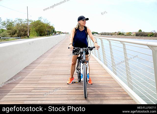 Active senior woman riding bicycle on promenade