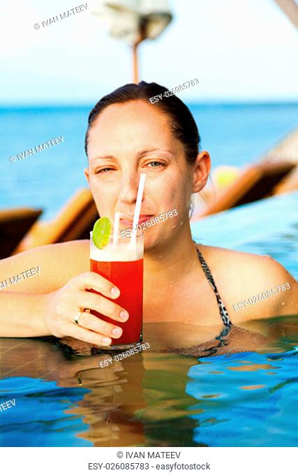 Young woman drinking Mai Thai Cocktail at the pool in a family hotel in Ko Samui, Thailand